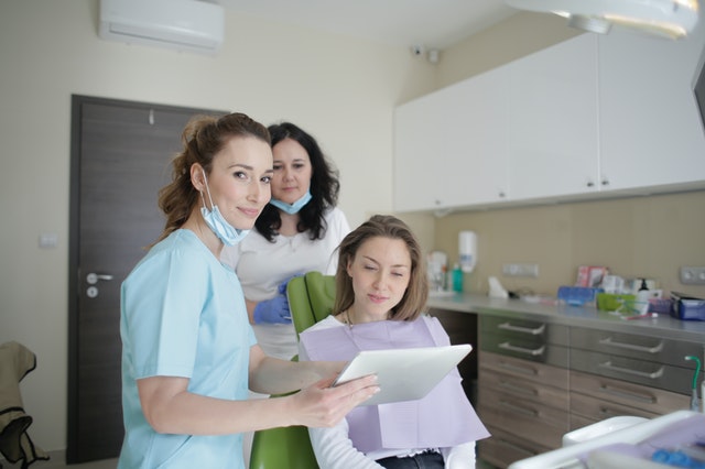 cheerful-stomatologist-and-assistant-showing-medical-report-3952125